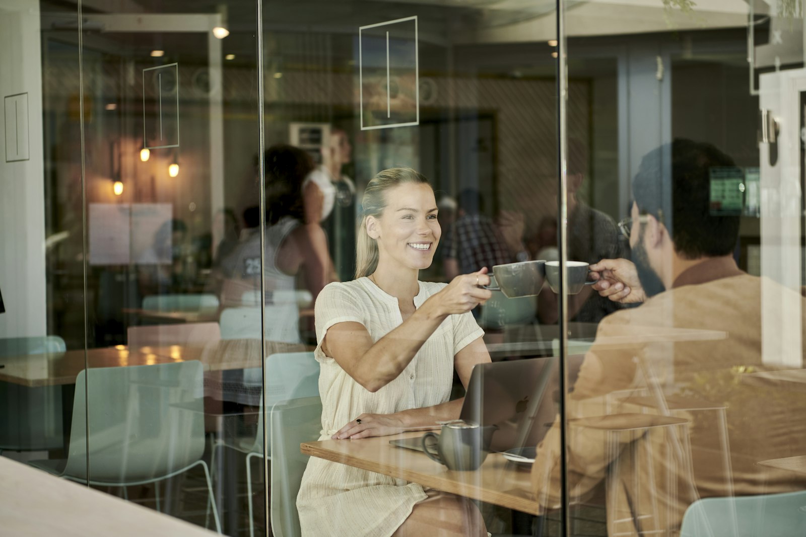 Due persone sedute in un bar guardano lo smartphone, il tipo di momento in cui nasce una recensione su Google.